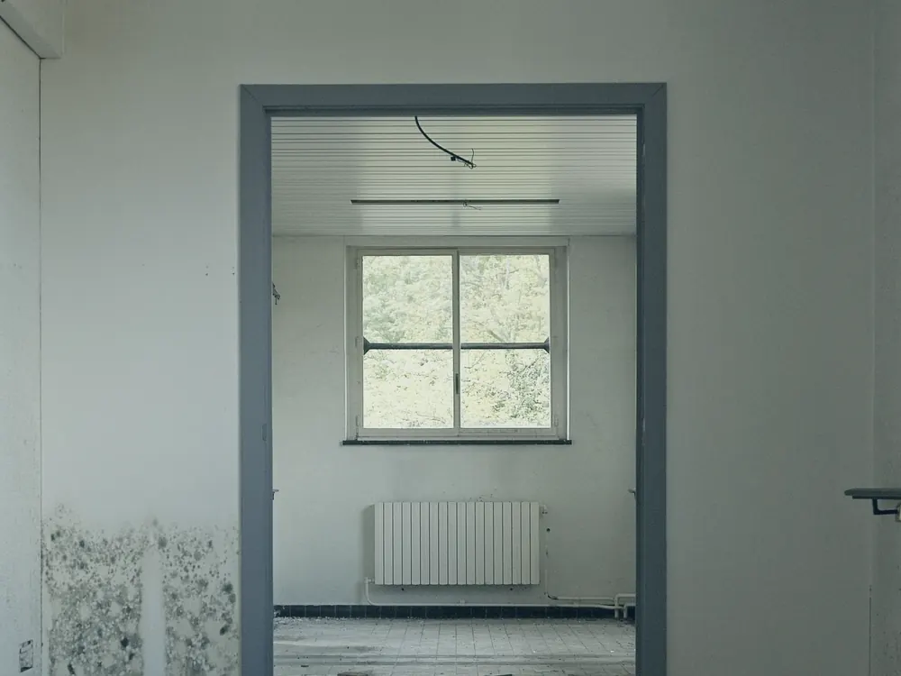 Überfluteter Fliesenboden in einem Kellerraum, an der Wand zeichnet sich Feuchtigkeit ab